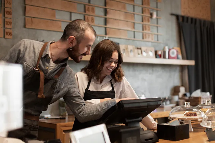 The male and female employees at the cafe handle the orders and business management using the POS and bill system
