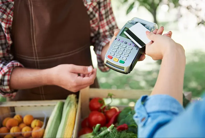 The woman shopping at the market makes easy and fast payments with the obligation
